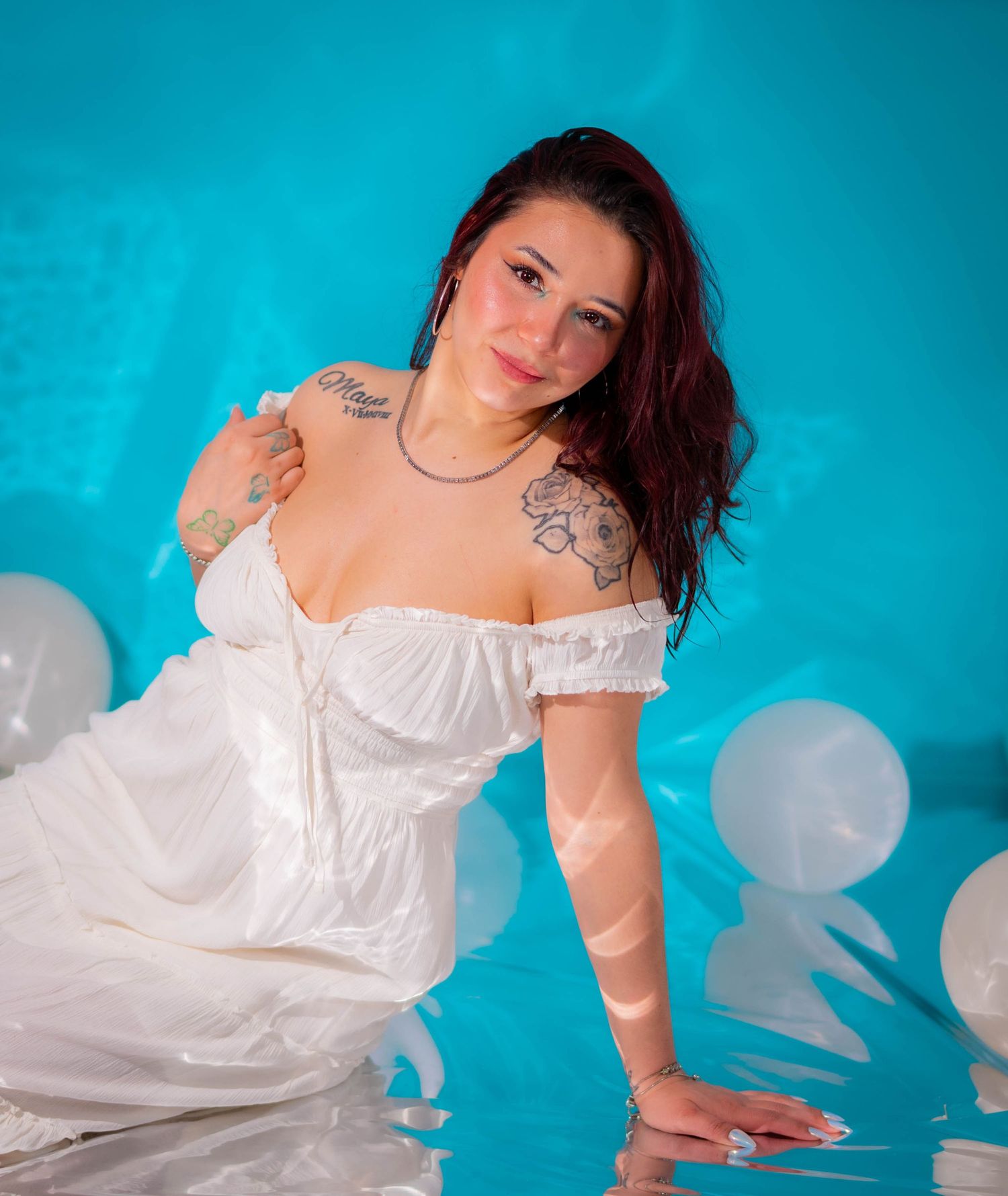 Dreamy boudoir photography with white dress against vibrant turquoise studio backdrop.