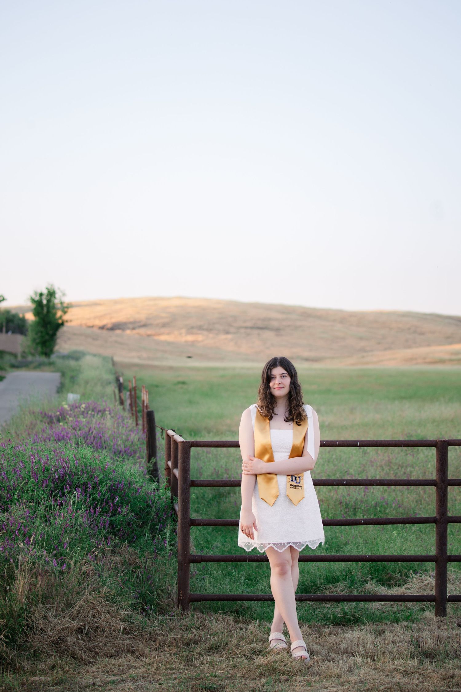 A series of photos showing a person in white dress sitting on a rustic wooden fence with rolling hills in the background.