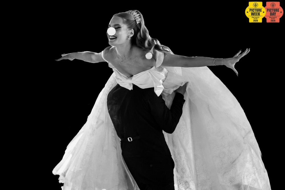 Black and white photo of couple dancing, woman in flowing white dress with arms outstretched.