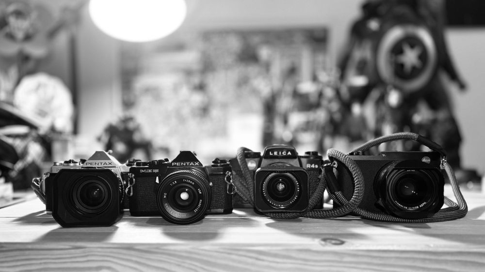 A collection of vintage film cameras lined up in black and white.