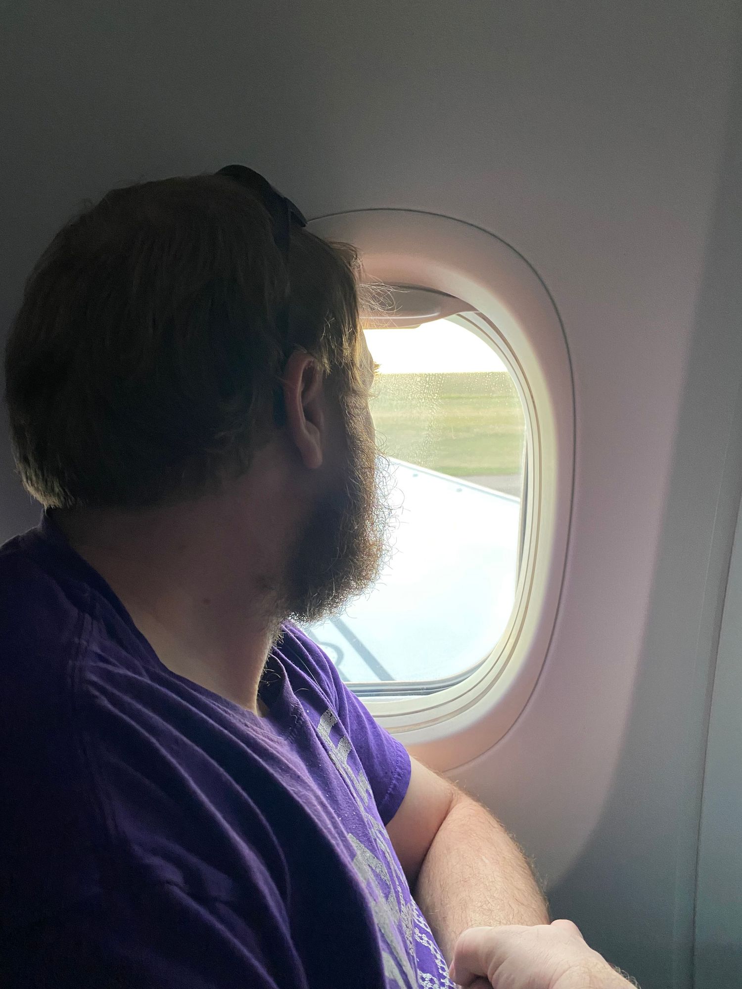 A passenger looks out an airplane window during flight.