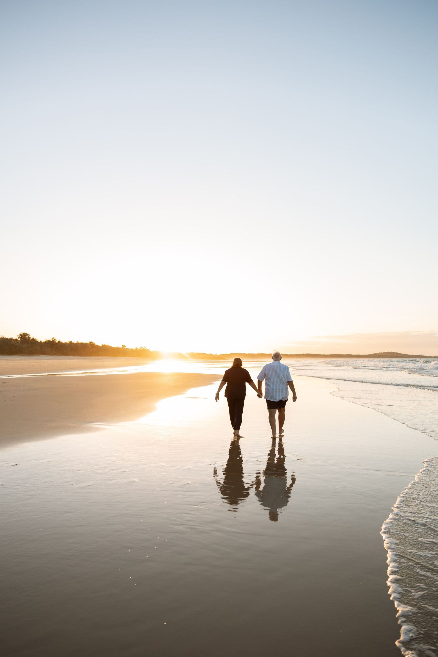 A older couple enjoying a walk along the beach at sunset. A true display of ever lasting love.
