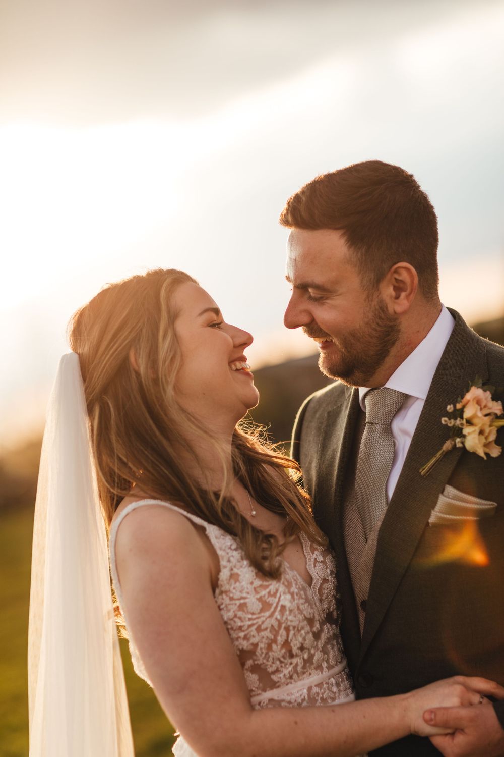 Candid wedding portrait capturing joyful laughter between newlyweds during golden hour.
