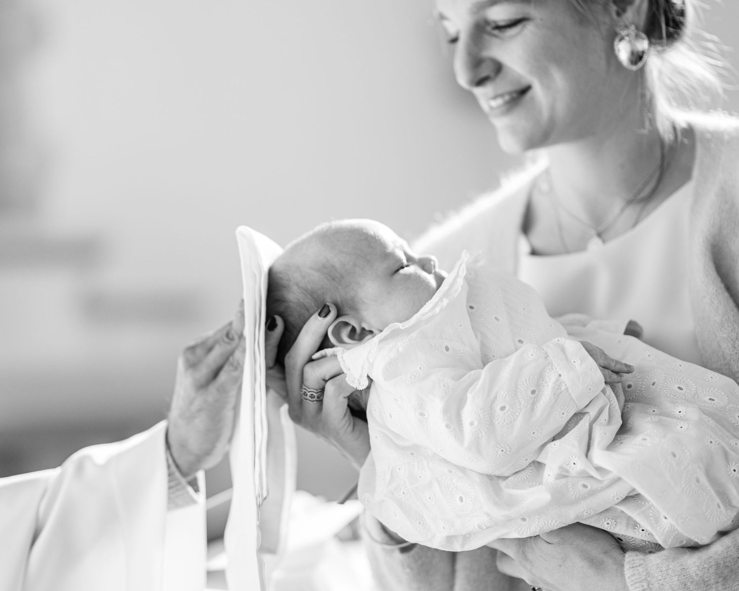 Tender moment between parent and newborn baby swaddled in white blanket.