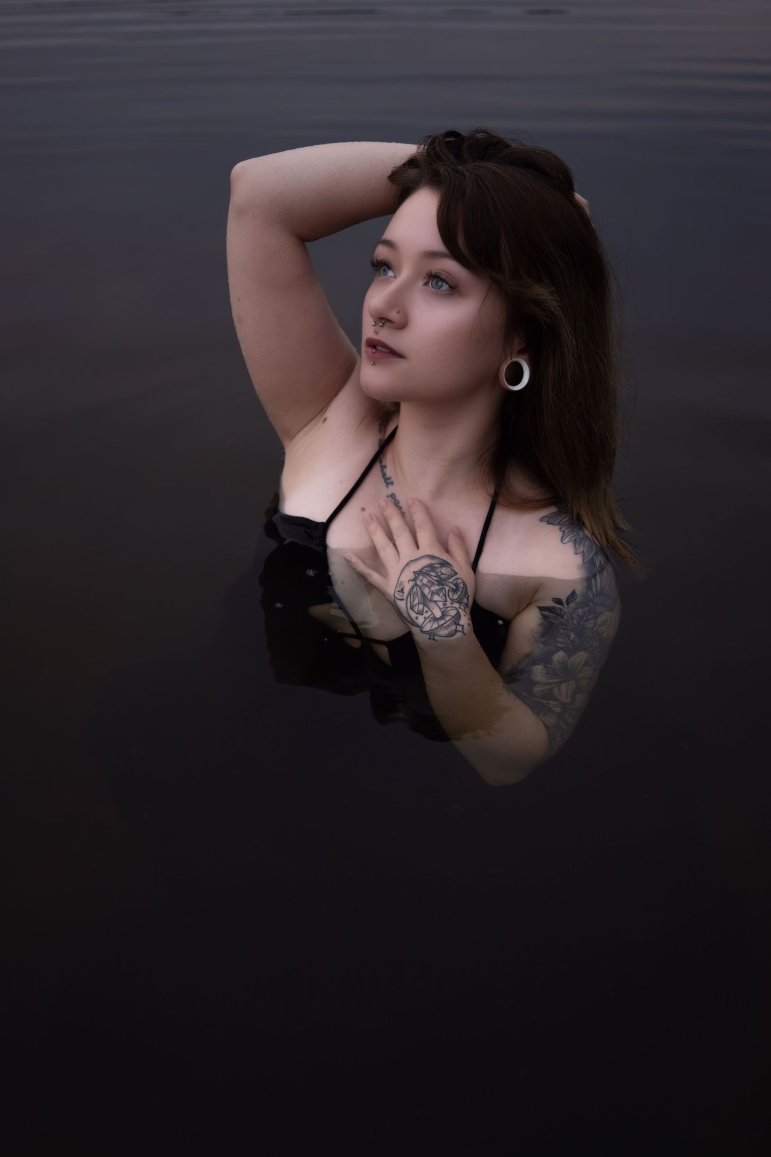 Dark and moody portrait photography in water featuring visible tattoo art.