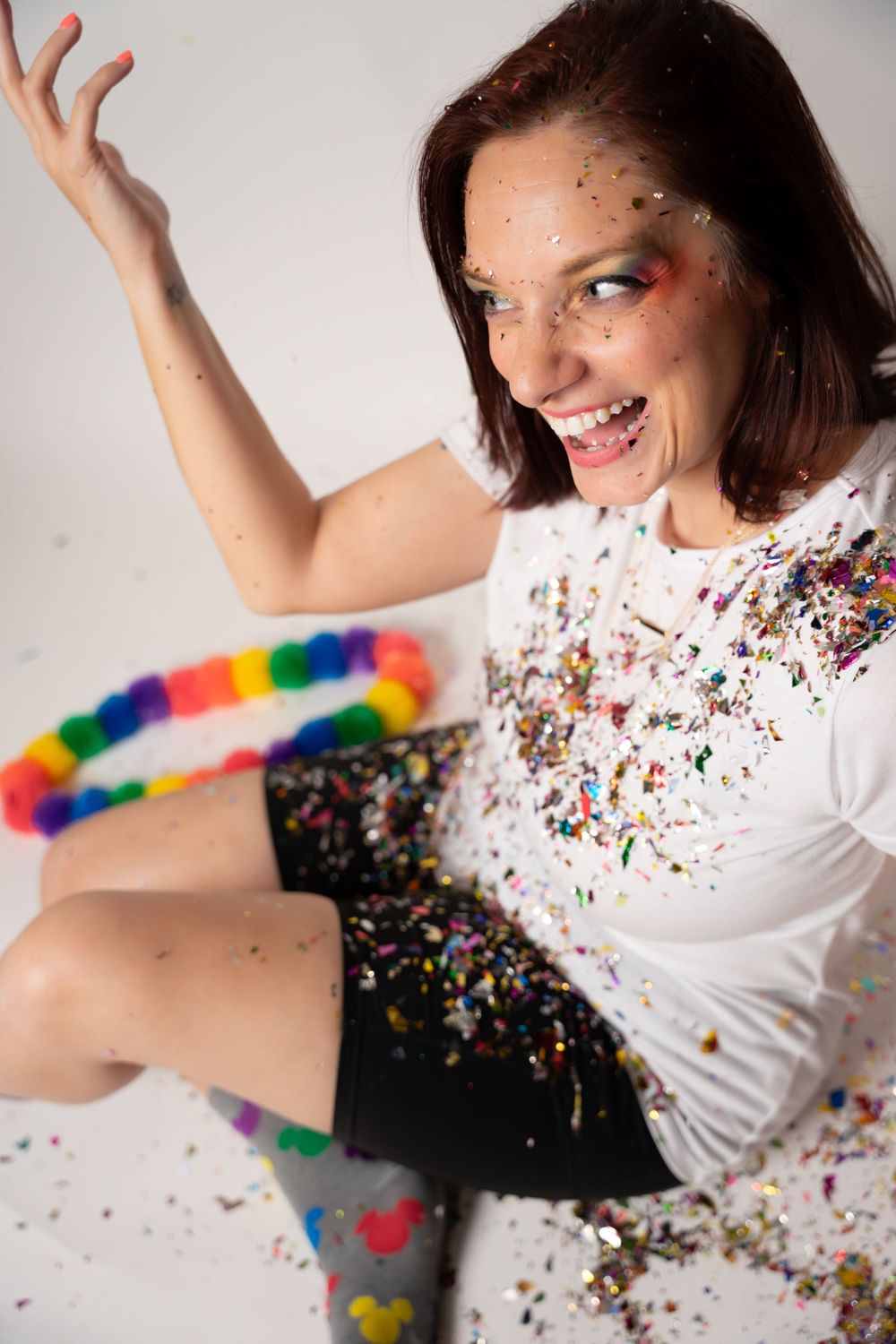 Dynamic portrait series with colorful makeup and glitter against white studio backdrop.