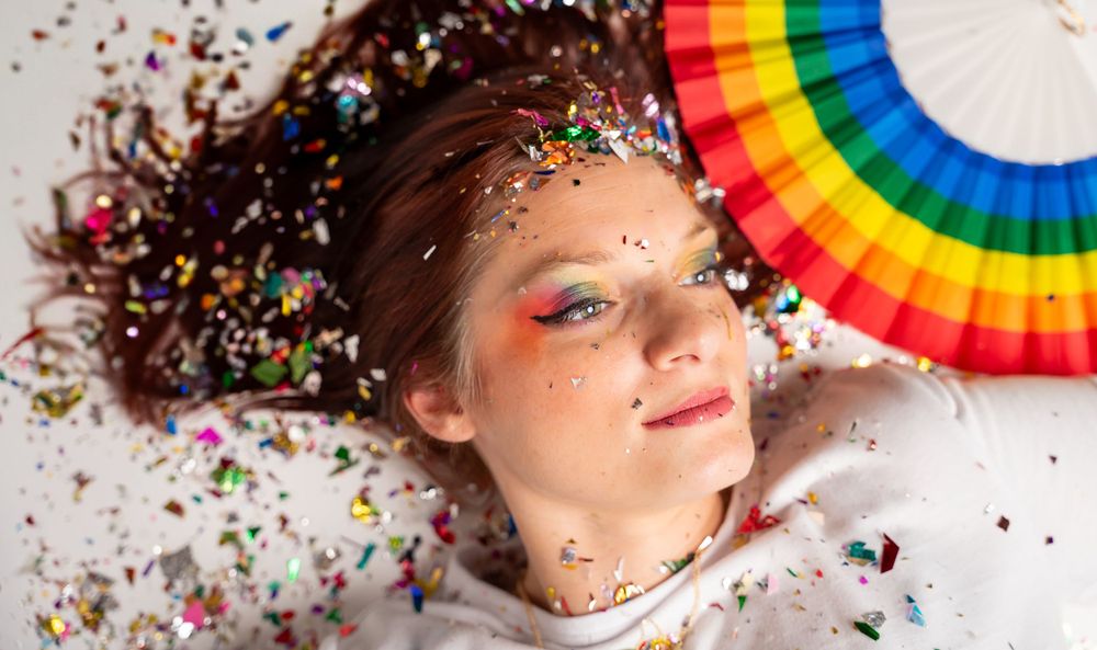 Overhead shots with rainbow pride elements and glitter against white background.