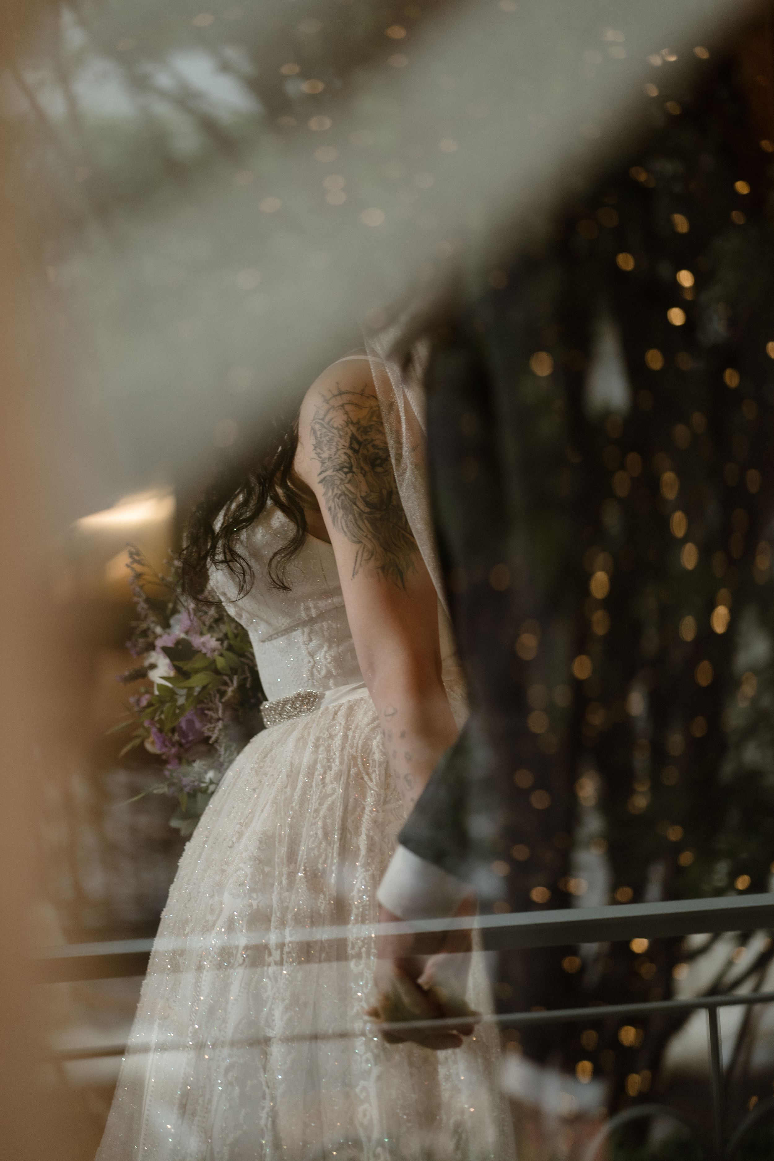 Ethereal wedding dress details captured through dreamy bokeh lights.