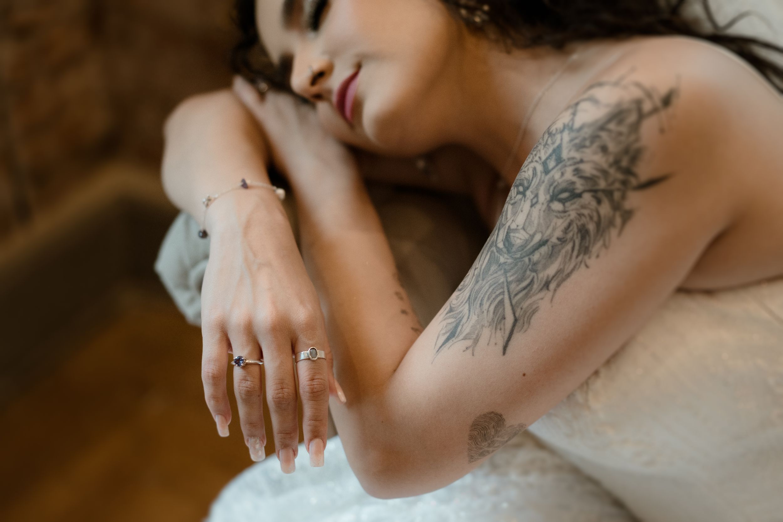 Close-up details of intricate floral tattoos and wedding dress lace.