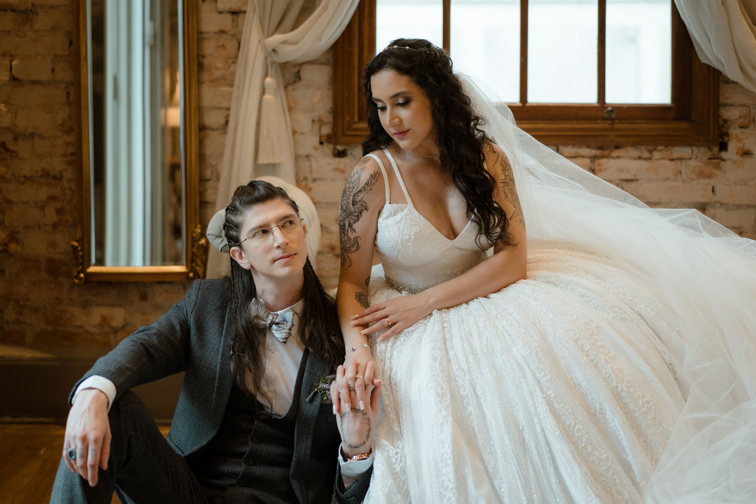 Romantic wedding couple poses on vintage sofa in rustic brick interior.