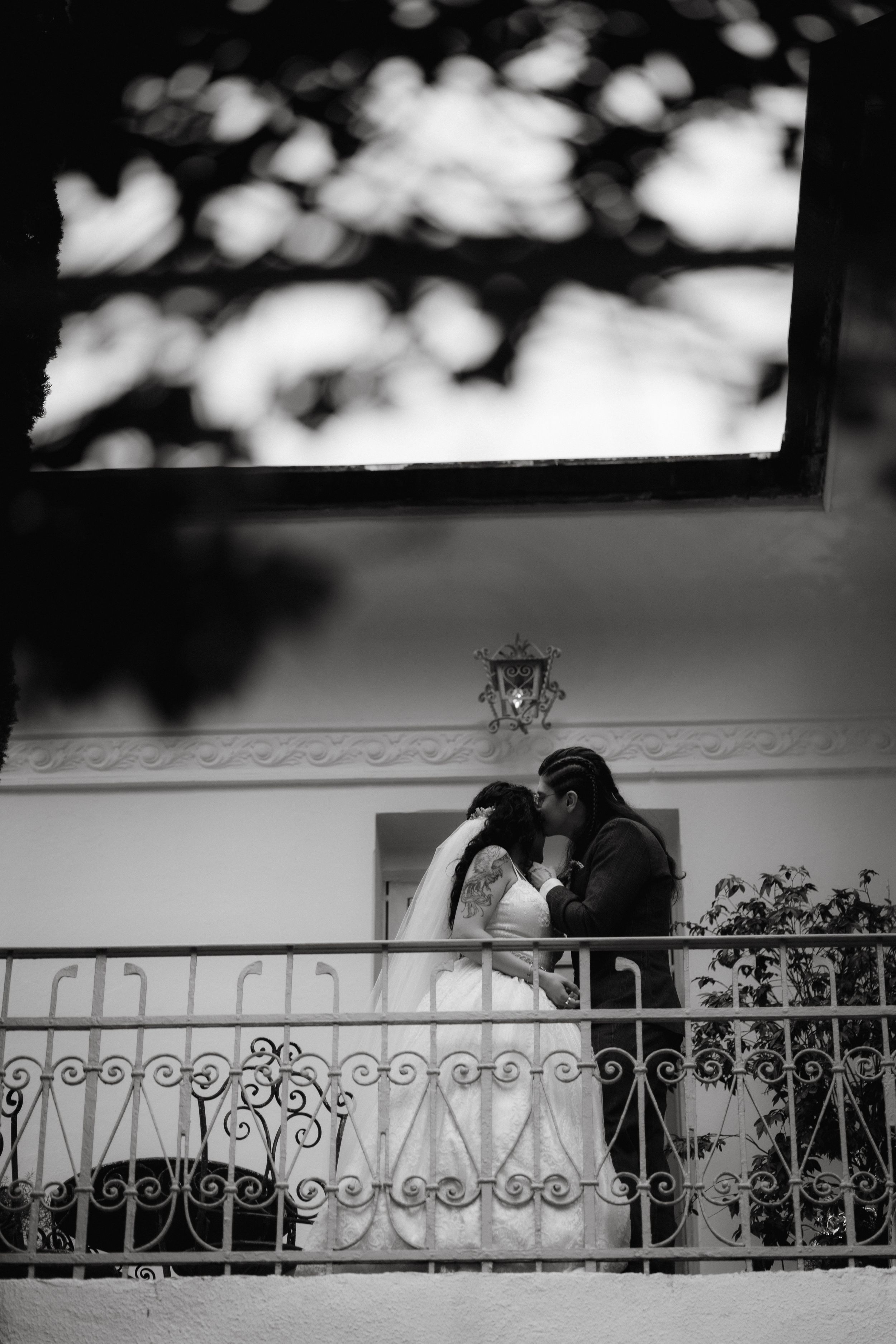 Black and white silhouette of couple on ornate balcony railing creates romantic atmosphere.