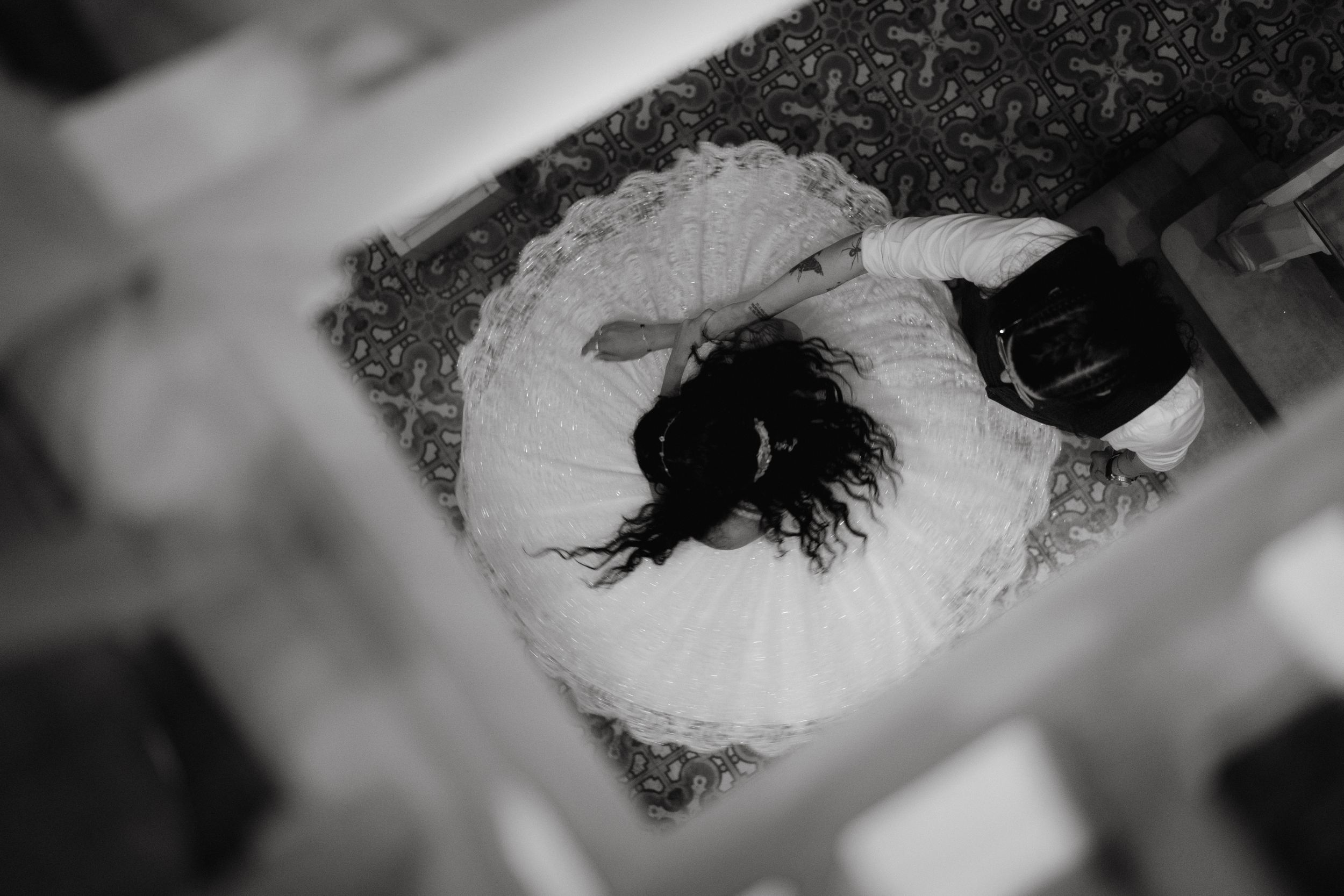 Overhead view of a bride's dress spread out on a patterned carpet.