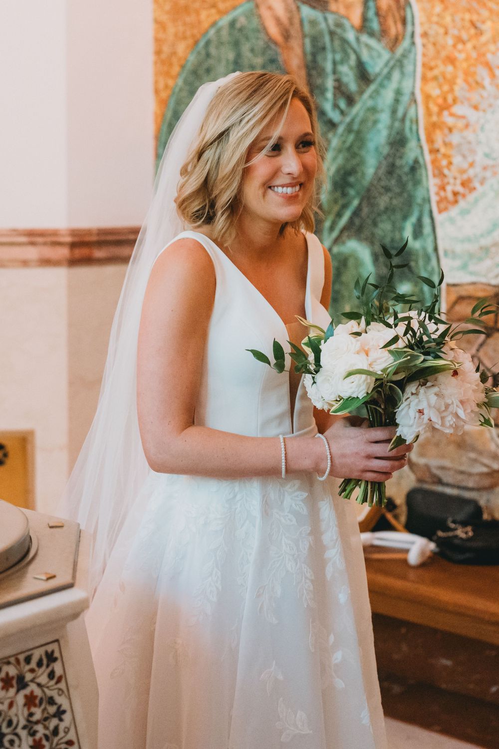 Close-up shots of a bride in a white wedding dress holding a bouquet of white flowers and greenery.