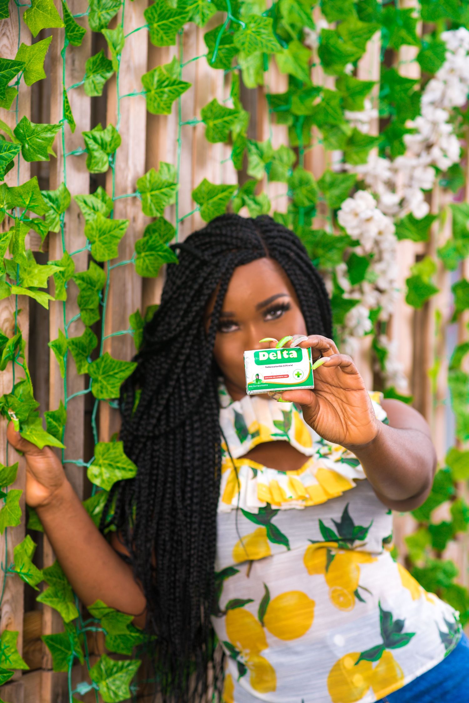 Lifestyle portrait holding gum package against wall with green vine leaves.