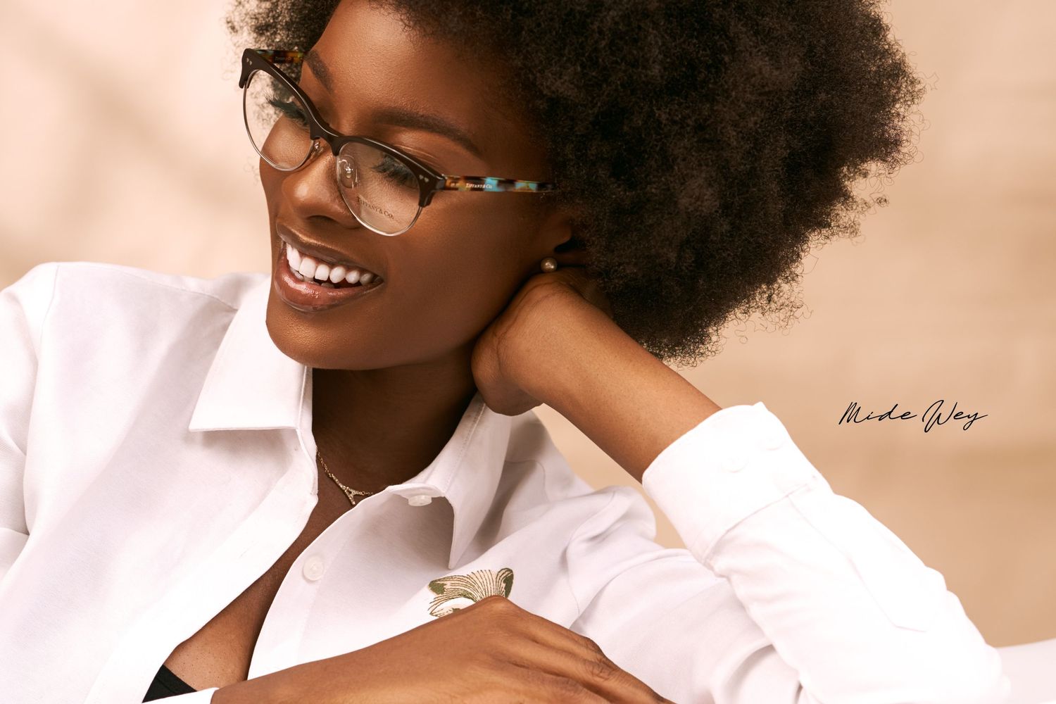 Professional headshots featuring natural hair and glasses against a warm background.