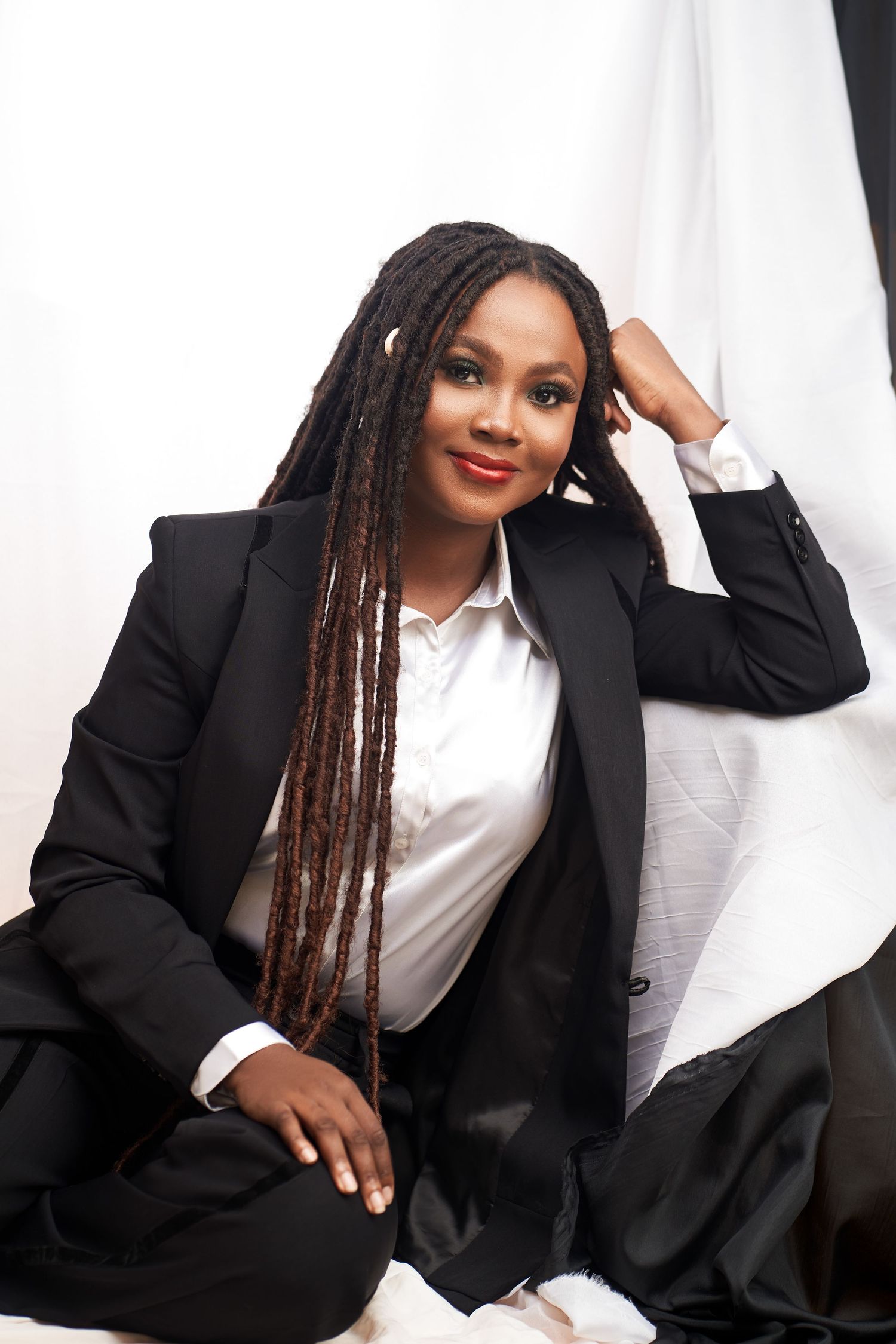 Professional portrait featuring long braids, black blazer, and white shirt against a white background.