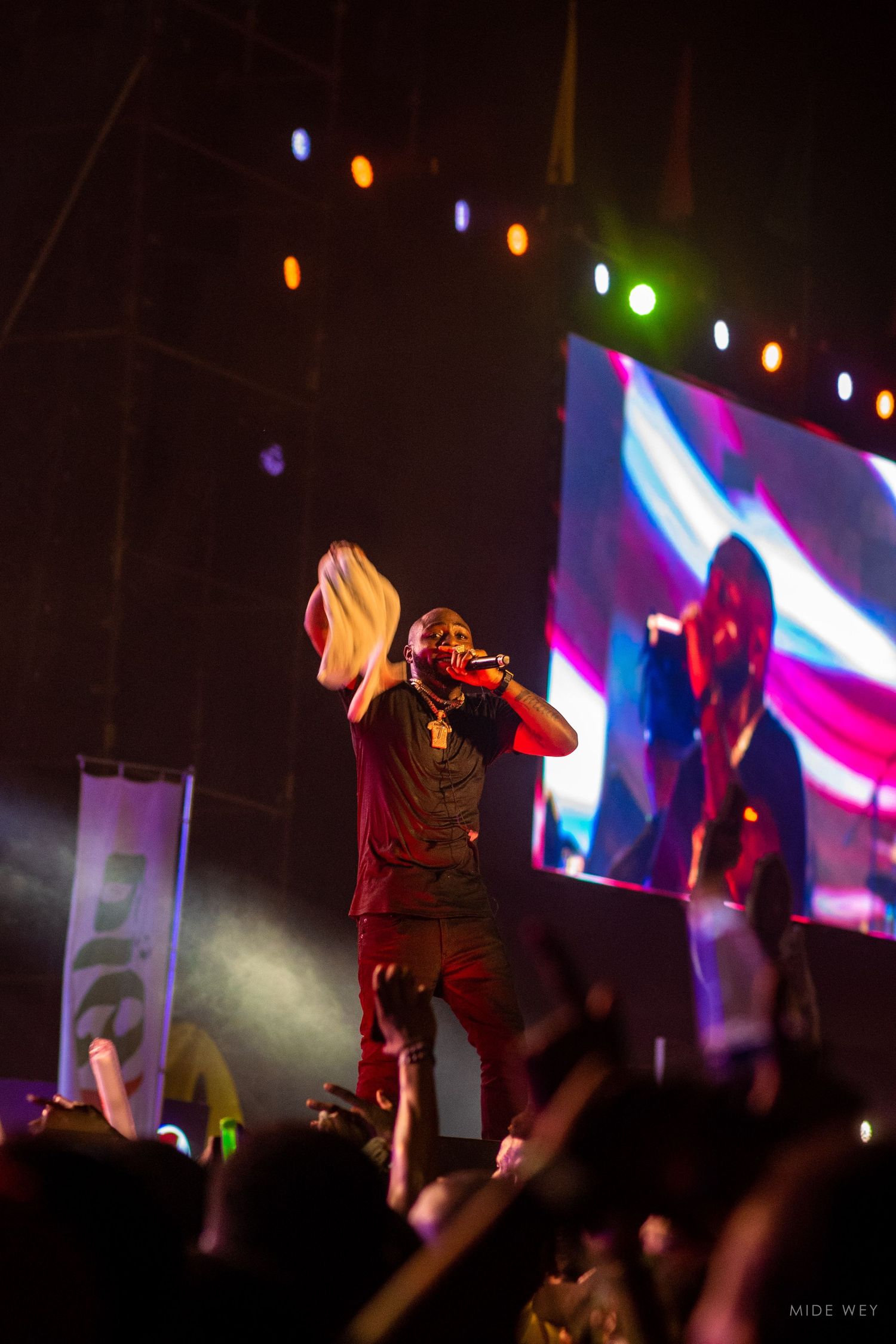 Concert performers silhouetted against colorful stage lights and LED screens.