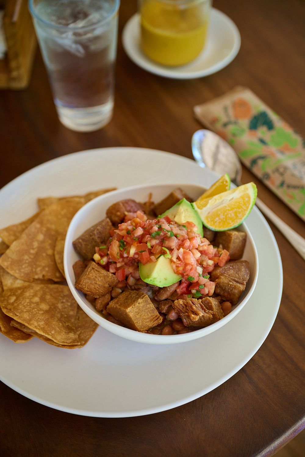 Mexican dish of fresh shrimp ceviche served with crispy tortilla chips on a white plate at a restaurant table.