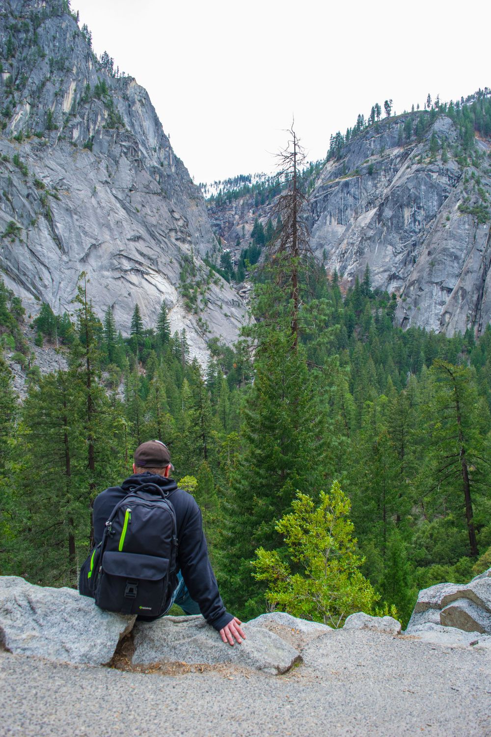 Hiker overlooking the dramatic granite cliffs and valley of Yosemite National Park.