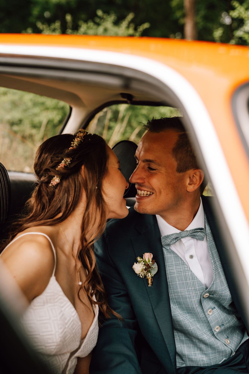 Intimate moments shared between newlyweds inside an orange vintage car.
