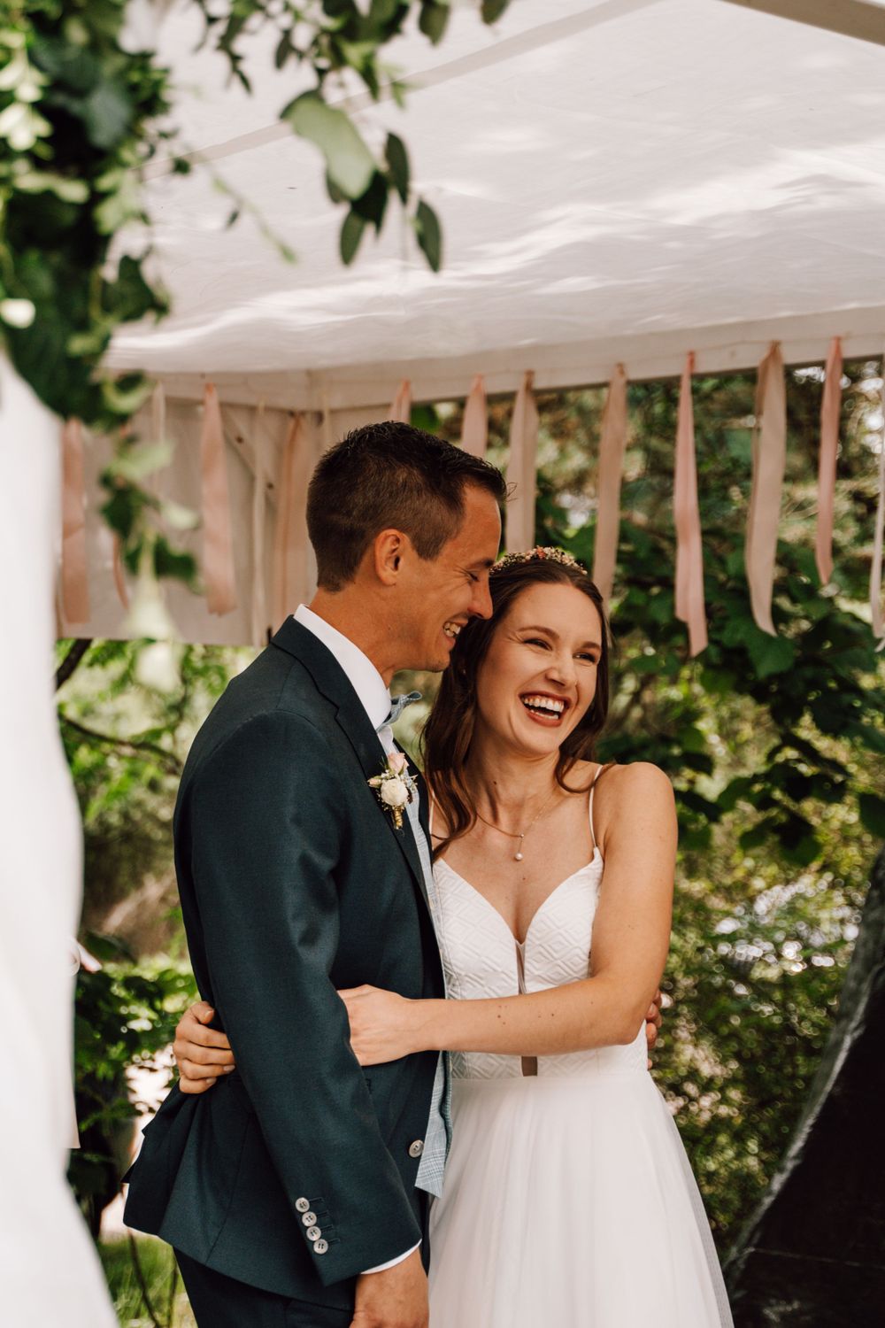 Candid laughter shared between newlyweds under a white tent.