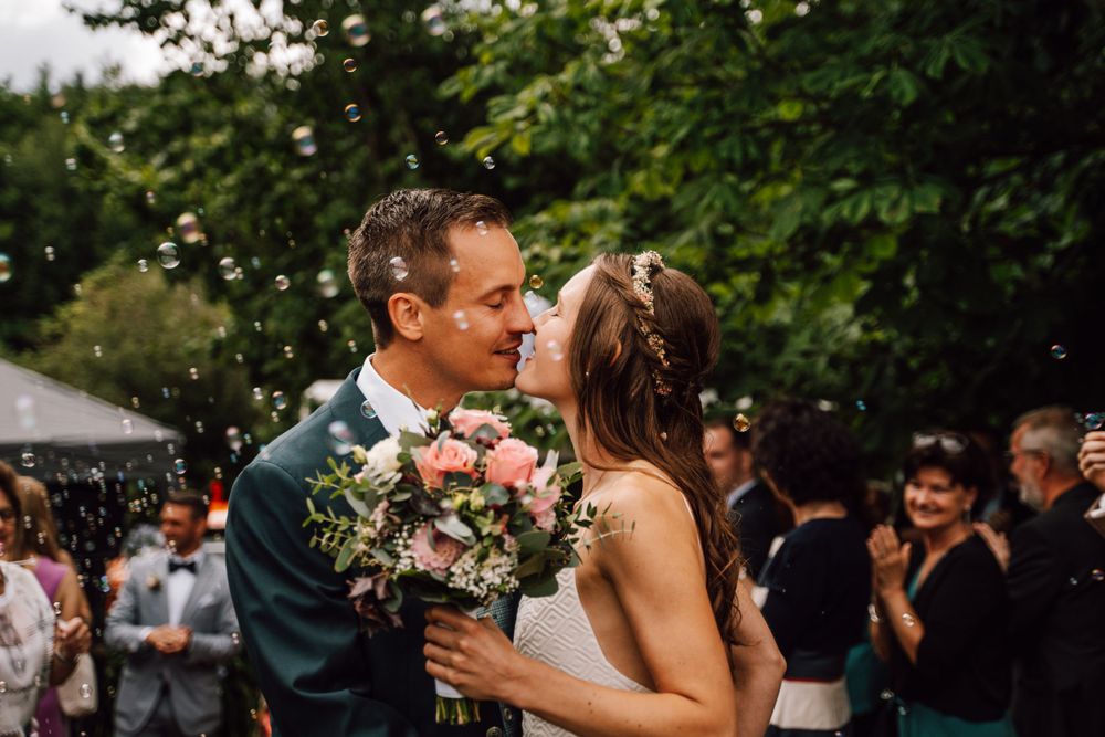 Wedding couple embraces in a romantic outdoor garden setting surrounded by greenery.