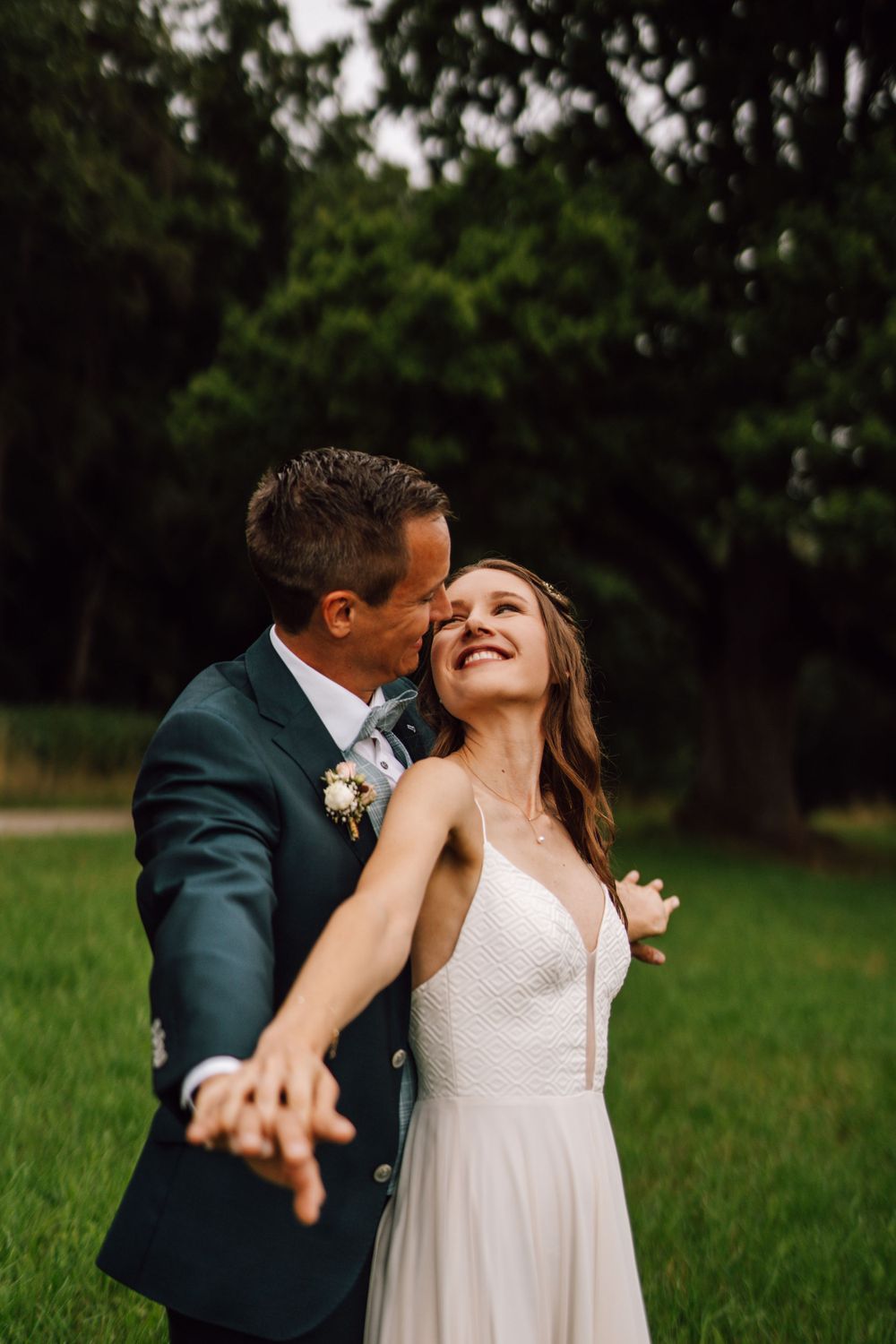 A couple shares a romantic moment in a green field during golden hour.
