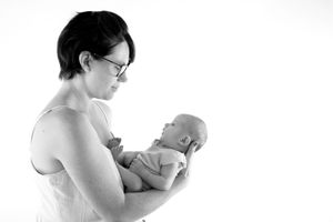 Minimalist black and white side view of mother cradling newborn baby.