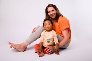 Mother in orange shirt sitting with young child in casual setting.