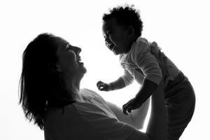 Silhouette portrait showing joyful interaction between mother and active toddler.