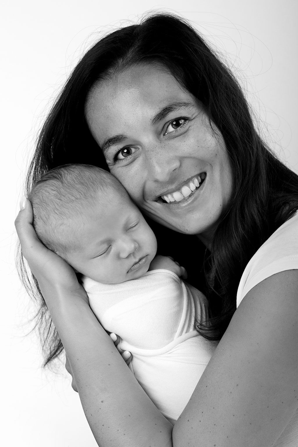 Black and white close-up of someone in white holding sleeping newborn baby.