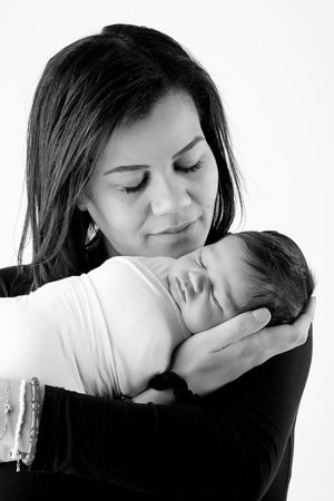 Black and white image of parent tenderly holding sleeping newborn.