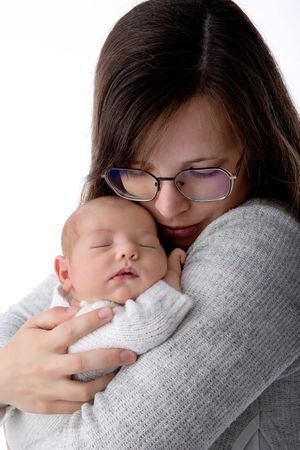 Intimate portrait of parent in glasses embracing sleeping newborn in soft lighting.