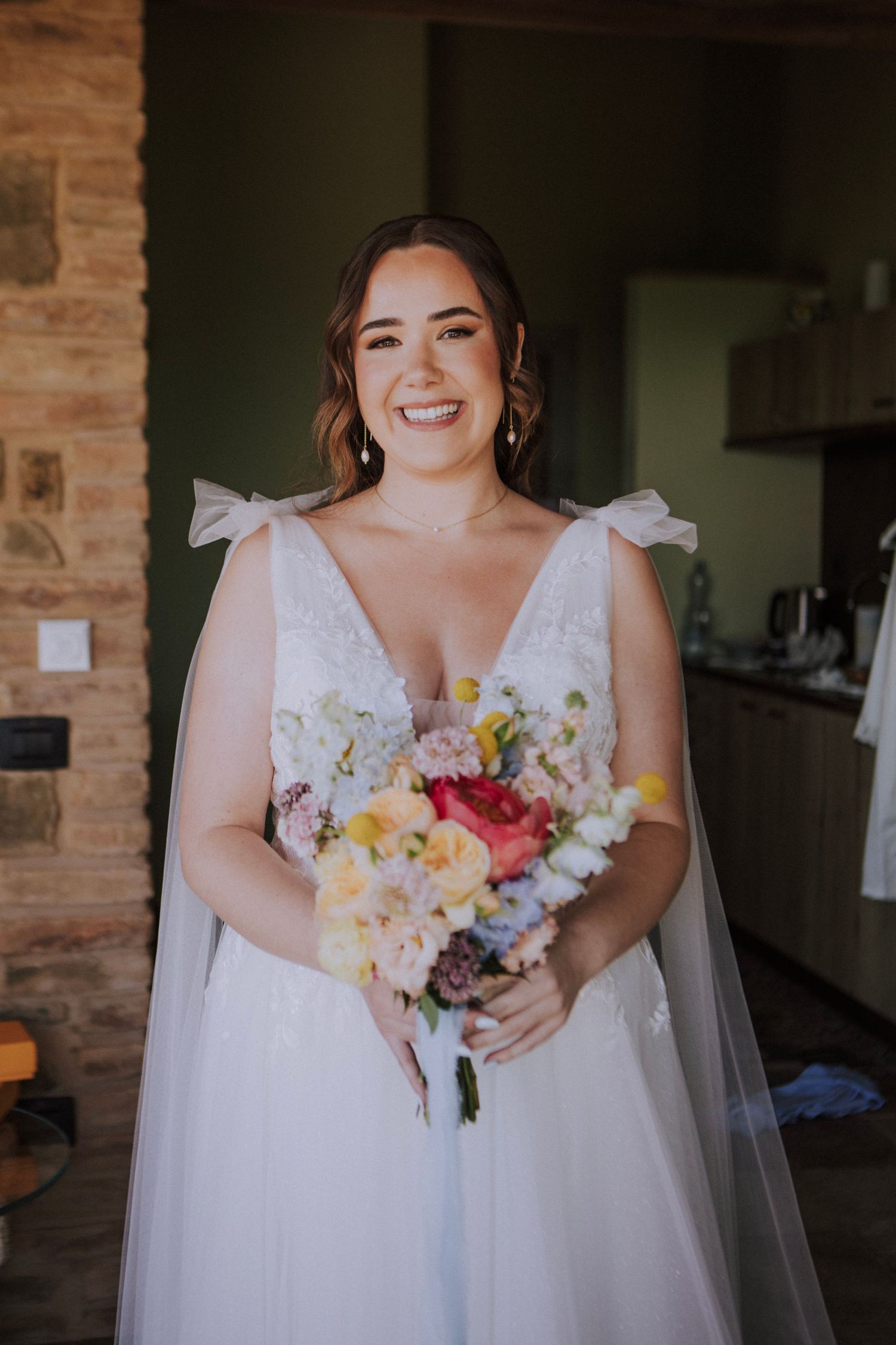 Bride smiling holding her bouquet photographed by Gianluca e Arianna Wedding Photographers in Umbria, Italy.