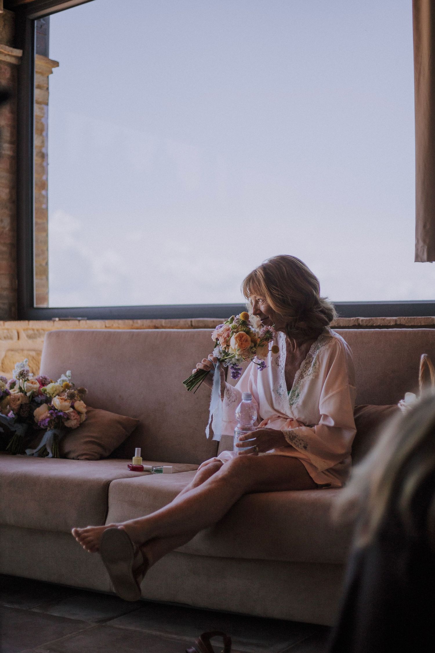 Bride's mother enjoying scent of flowers at   Perugia Vecchia Relais photographed by Gianluca e Arianna Wedding Photographers in Umbria.