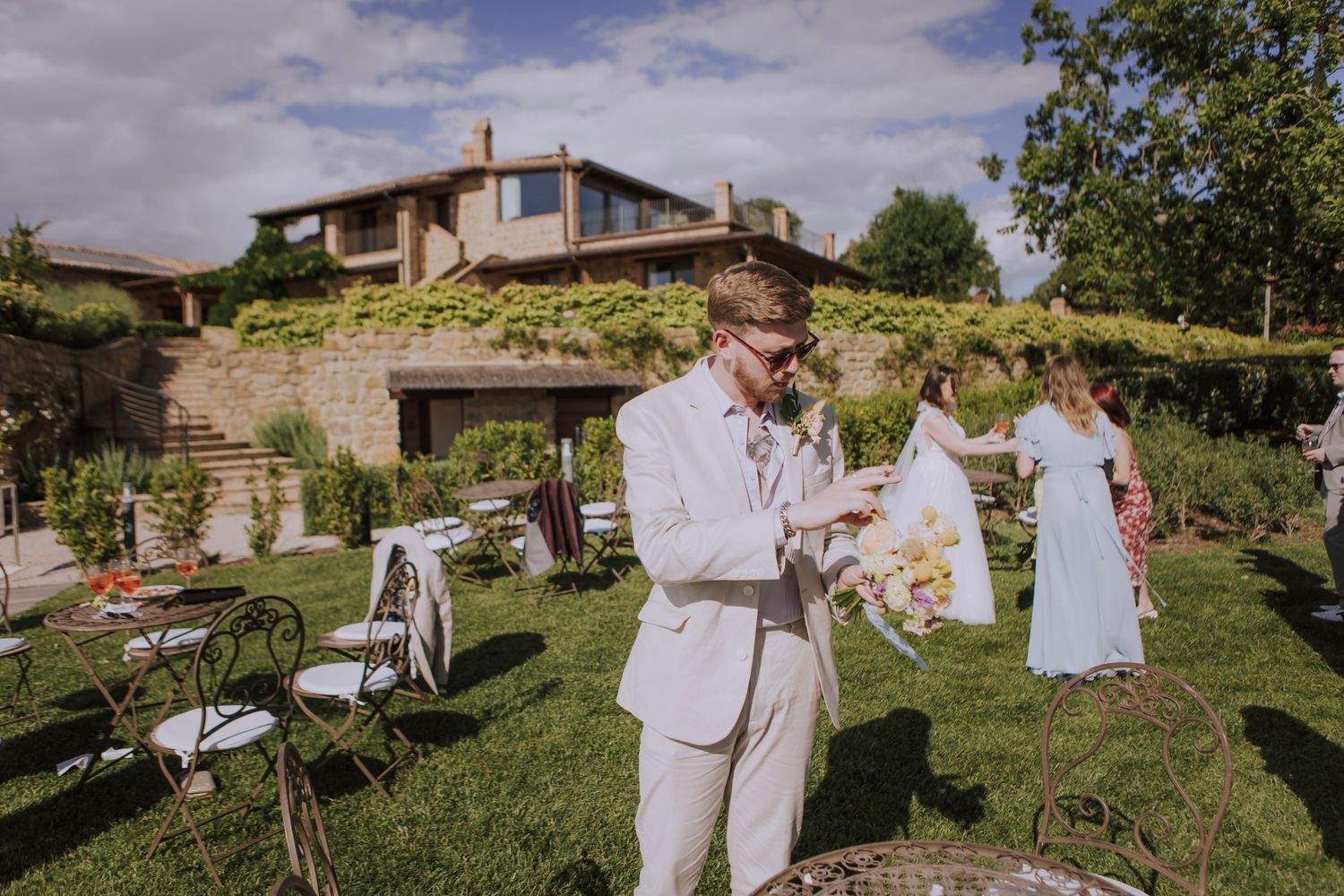 Outdoor wedding celebration at rustic venue with stone walls and greenery.
