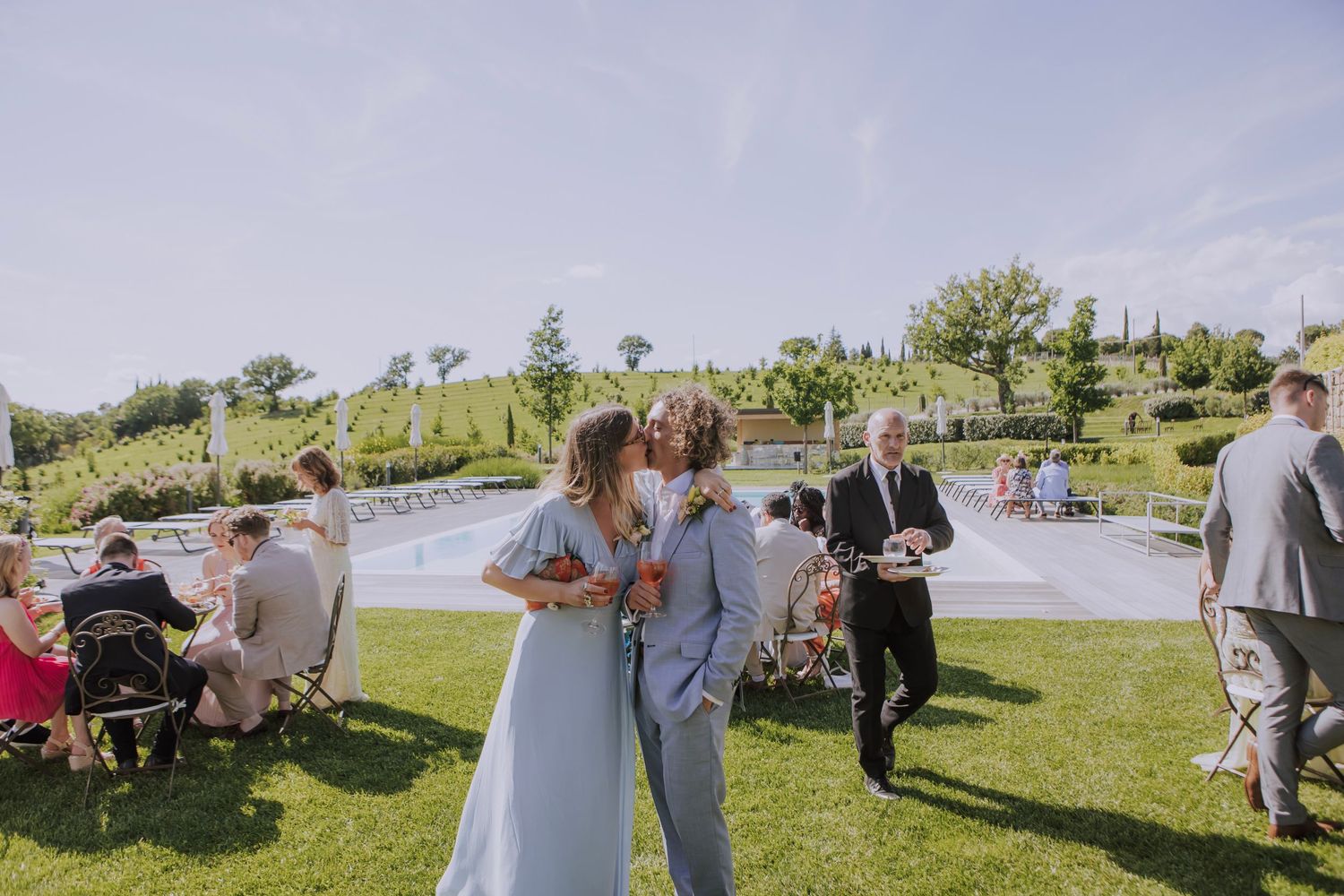 Outdoor wedding reception on grassy venue with guests mingling.