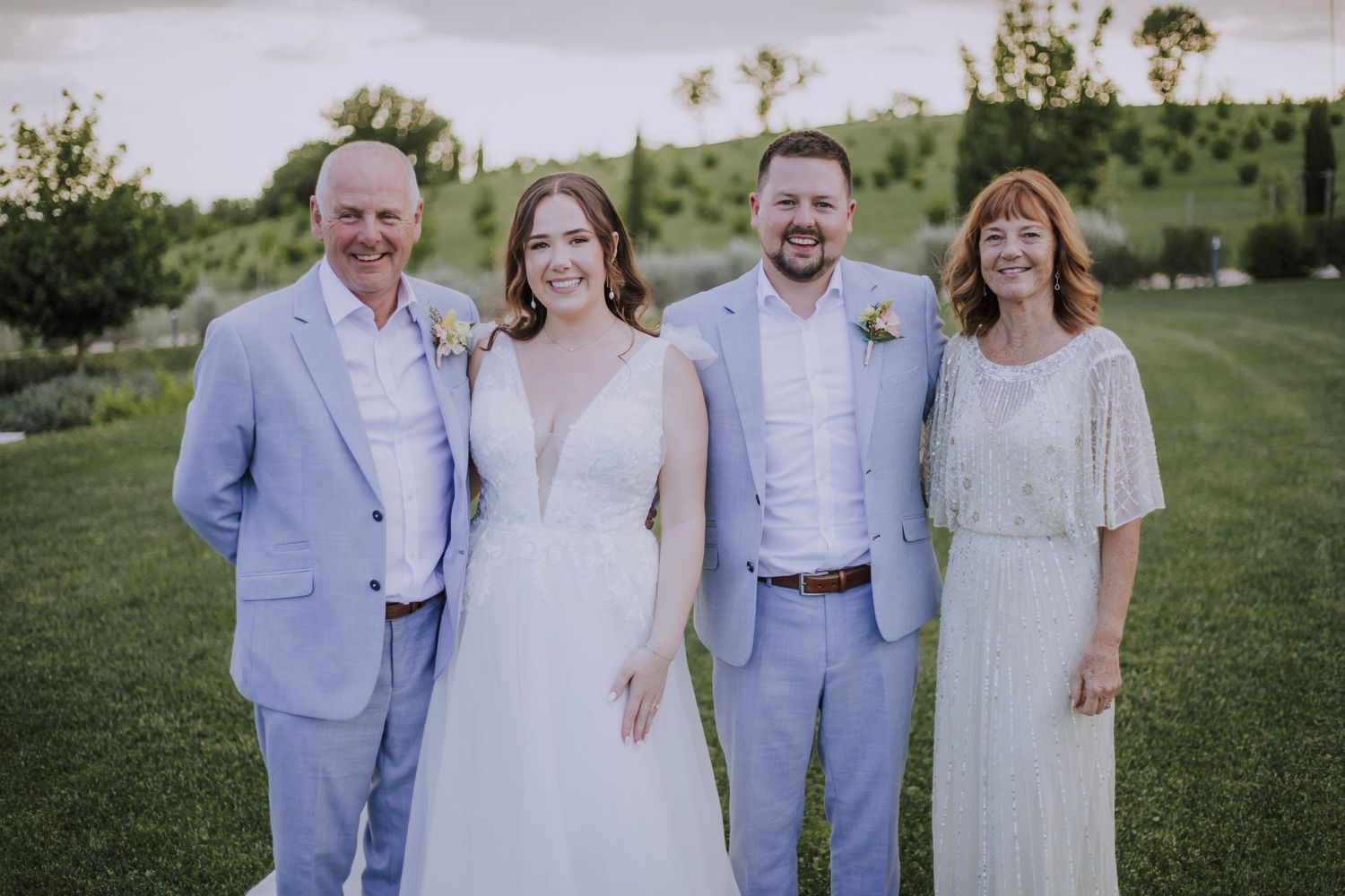 Wedding party portrait with couple and family members in coordinating light blue attire.