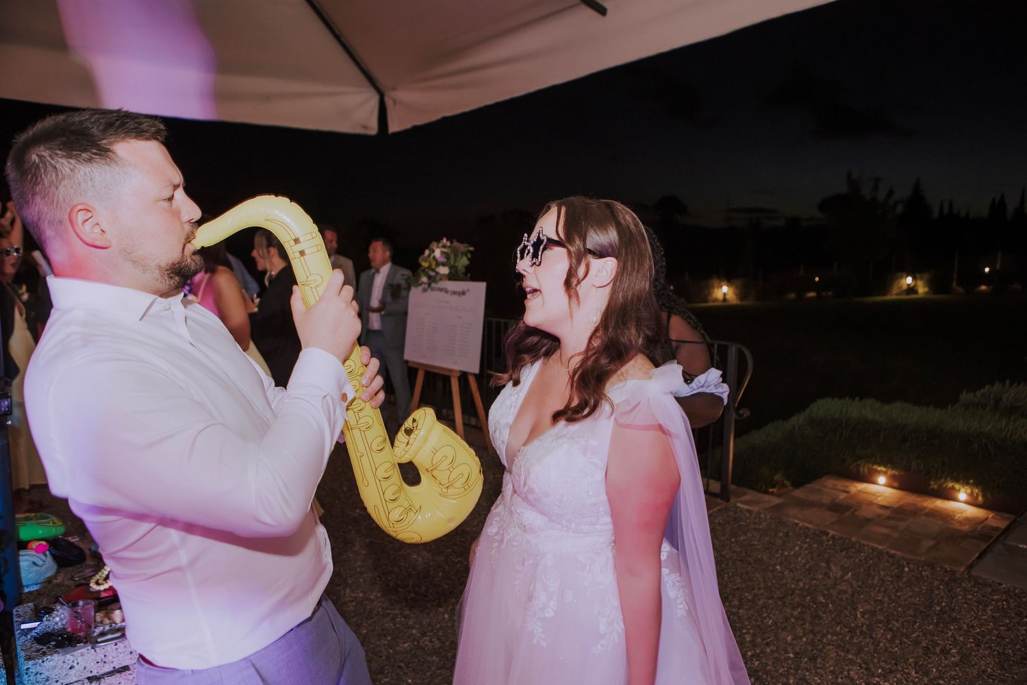 Celebratory moment with saxophone at outdoor evening wedding reception.
