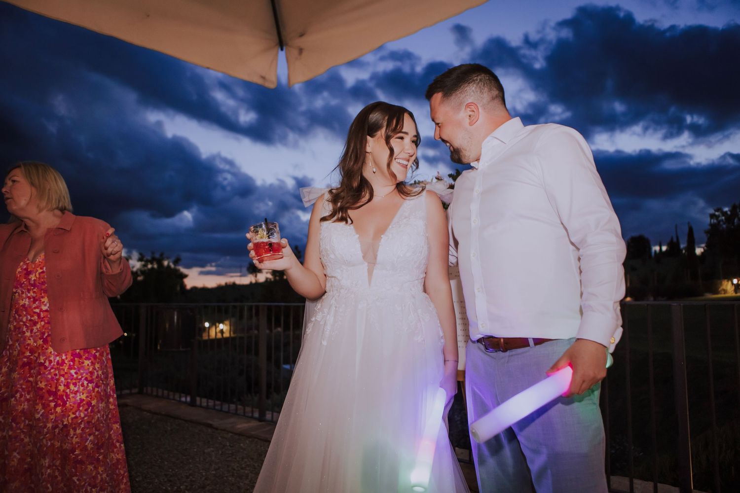 Couple sharing an intimate moment during their outdoor wedding reception against a twilight sky.