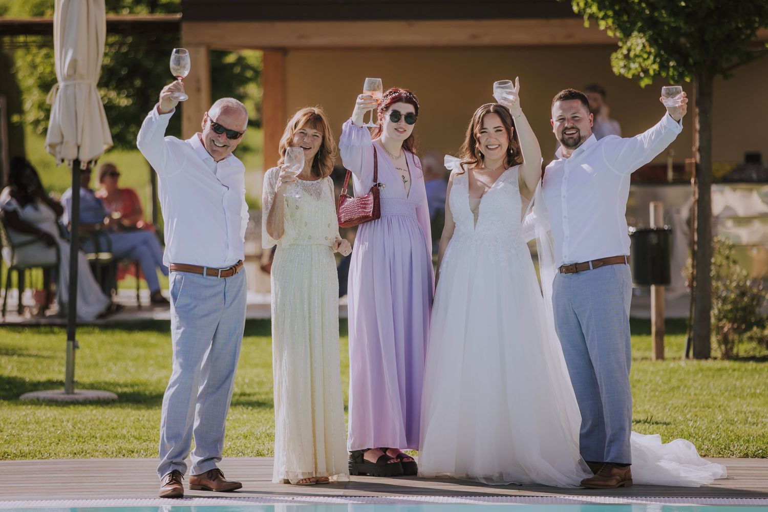 Wedding party celebrating on outdoor stage with arms raised in celebration.