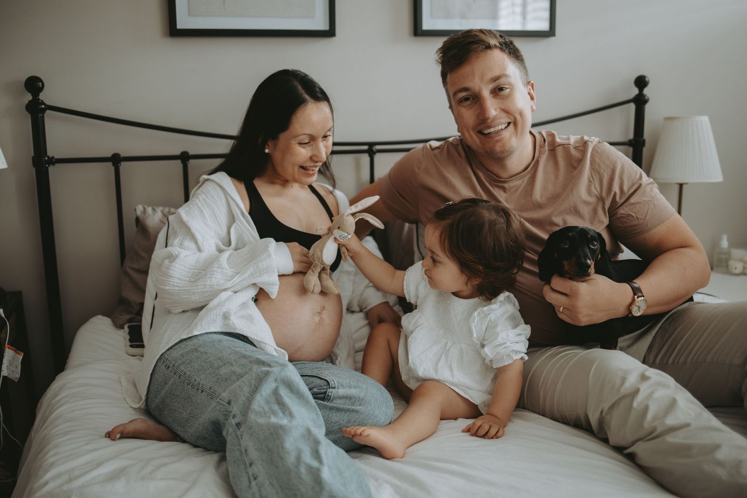 Family enjoying playful moments together on a cozy bed in a bright bedroom.
