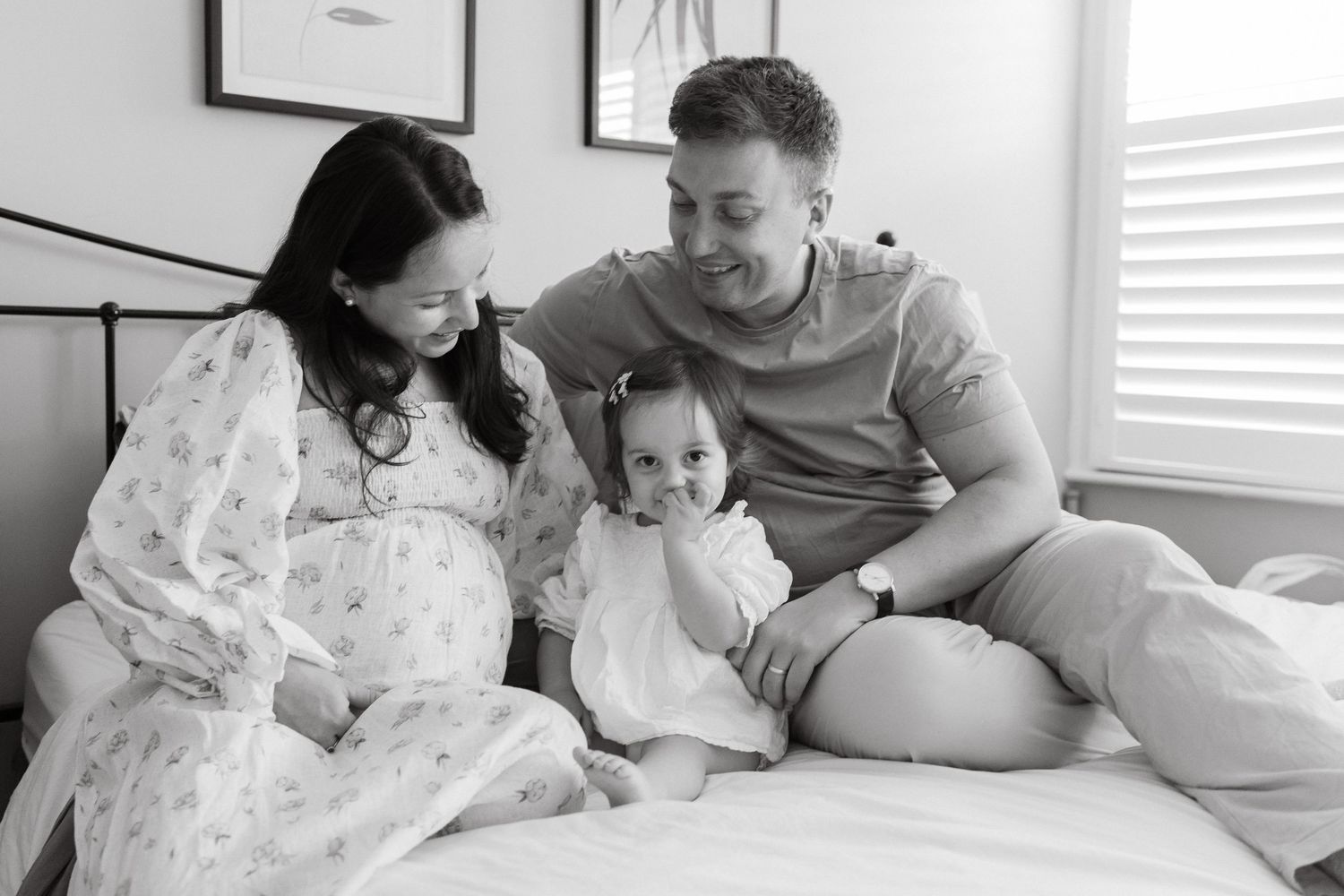 Family sharing intimate moments together on bed in bright sunlit room.