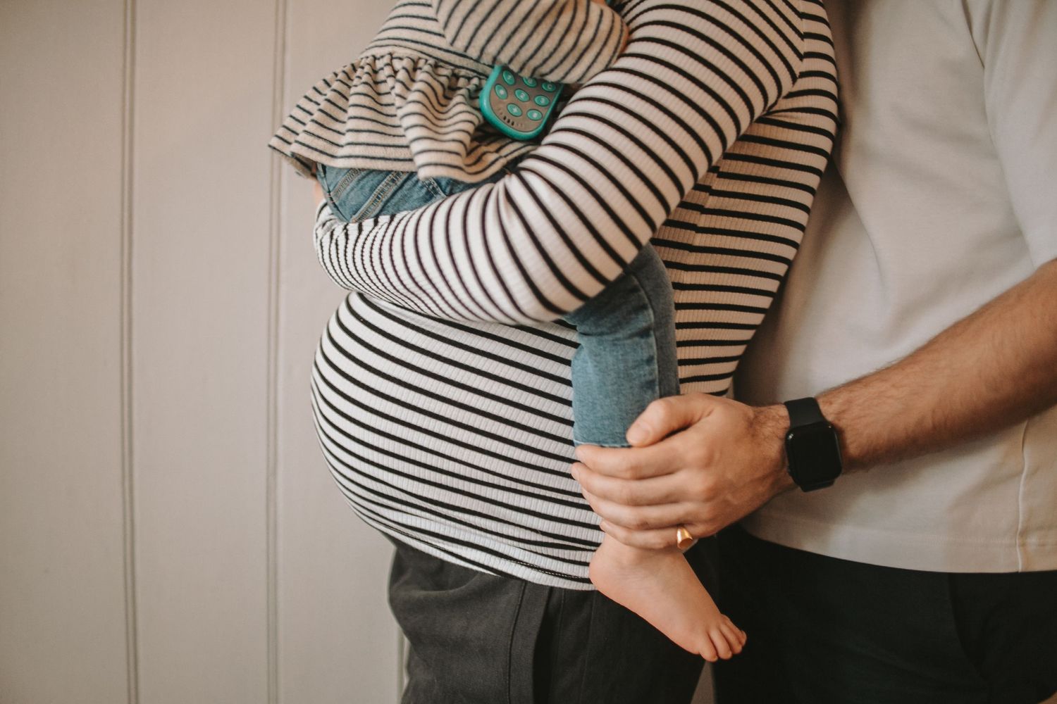Close-up of striped shirt and denim while holding child.
