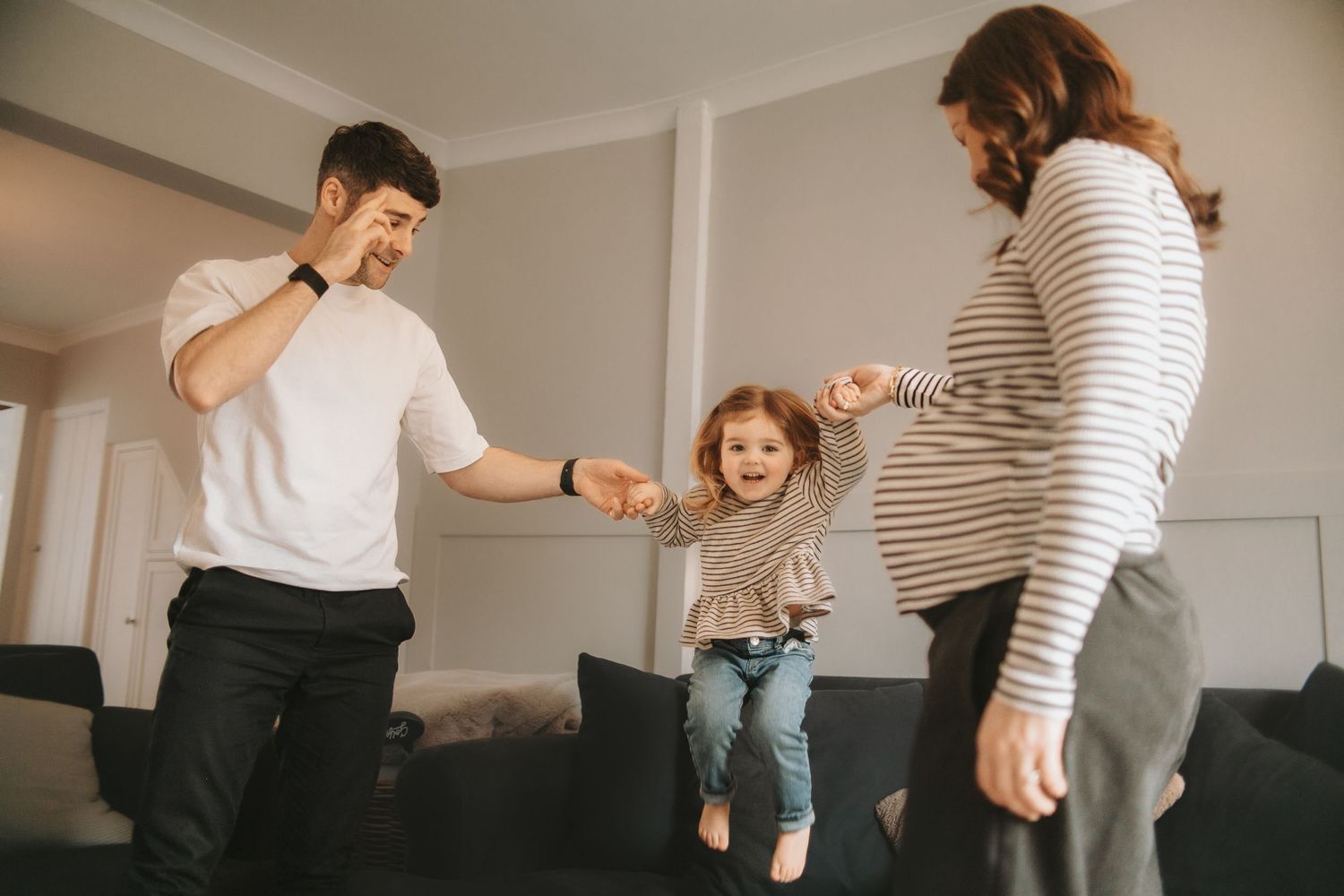 Family playing and jumping together in living room.