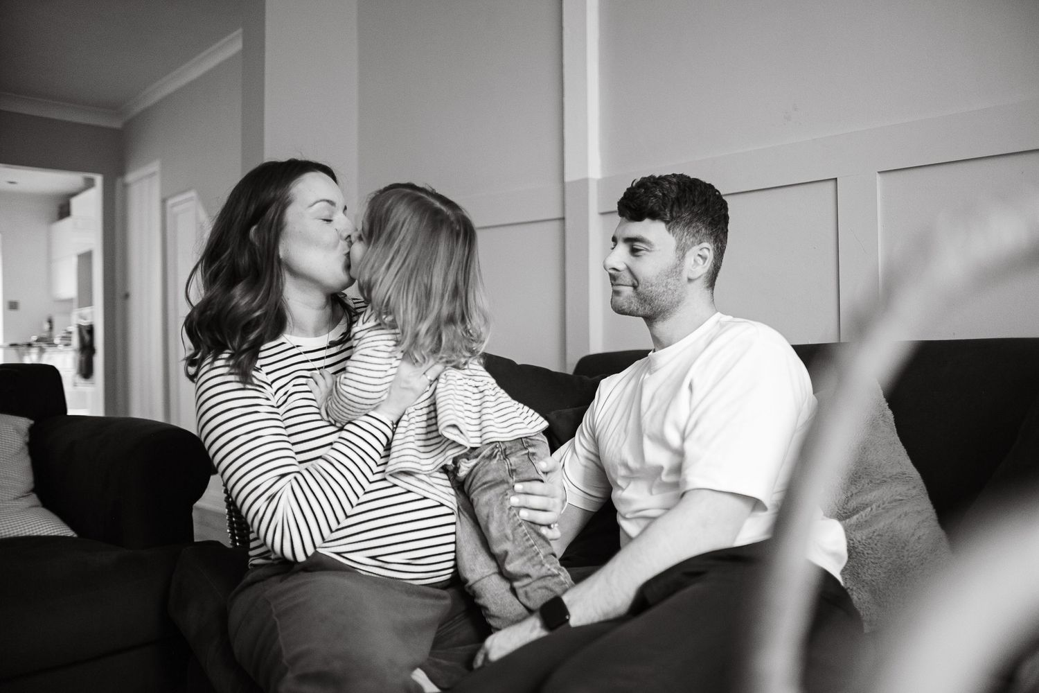 Black and white photo of family relaxing on couch together.