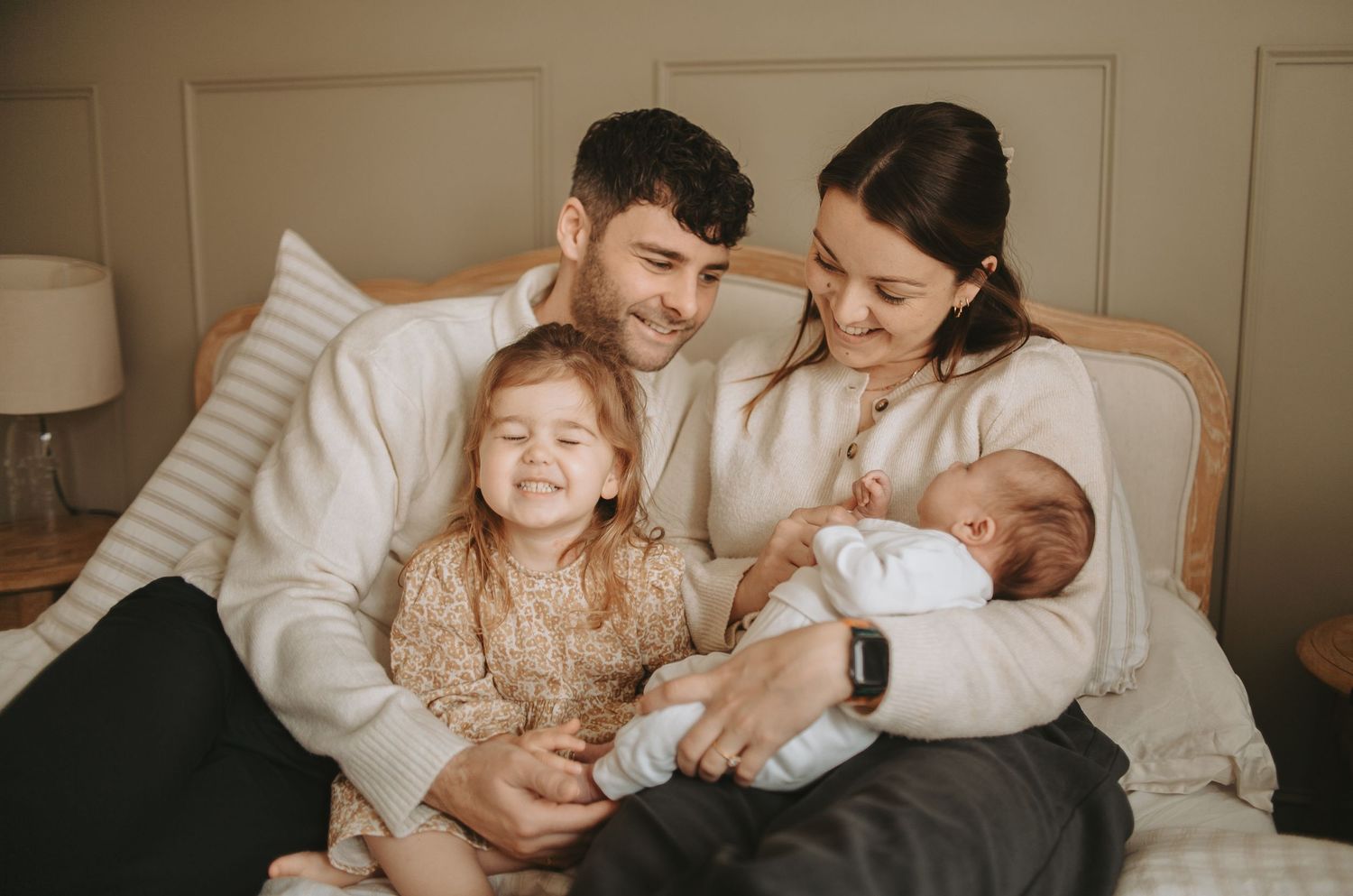 A family of four sharing an intimate moment together on a bed.