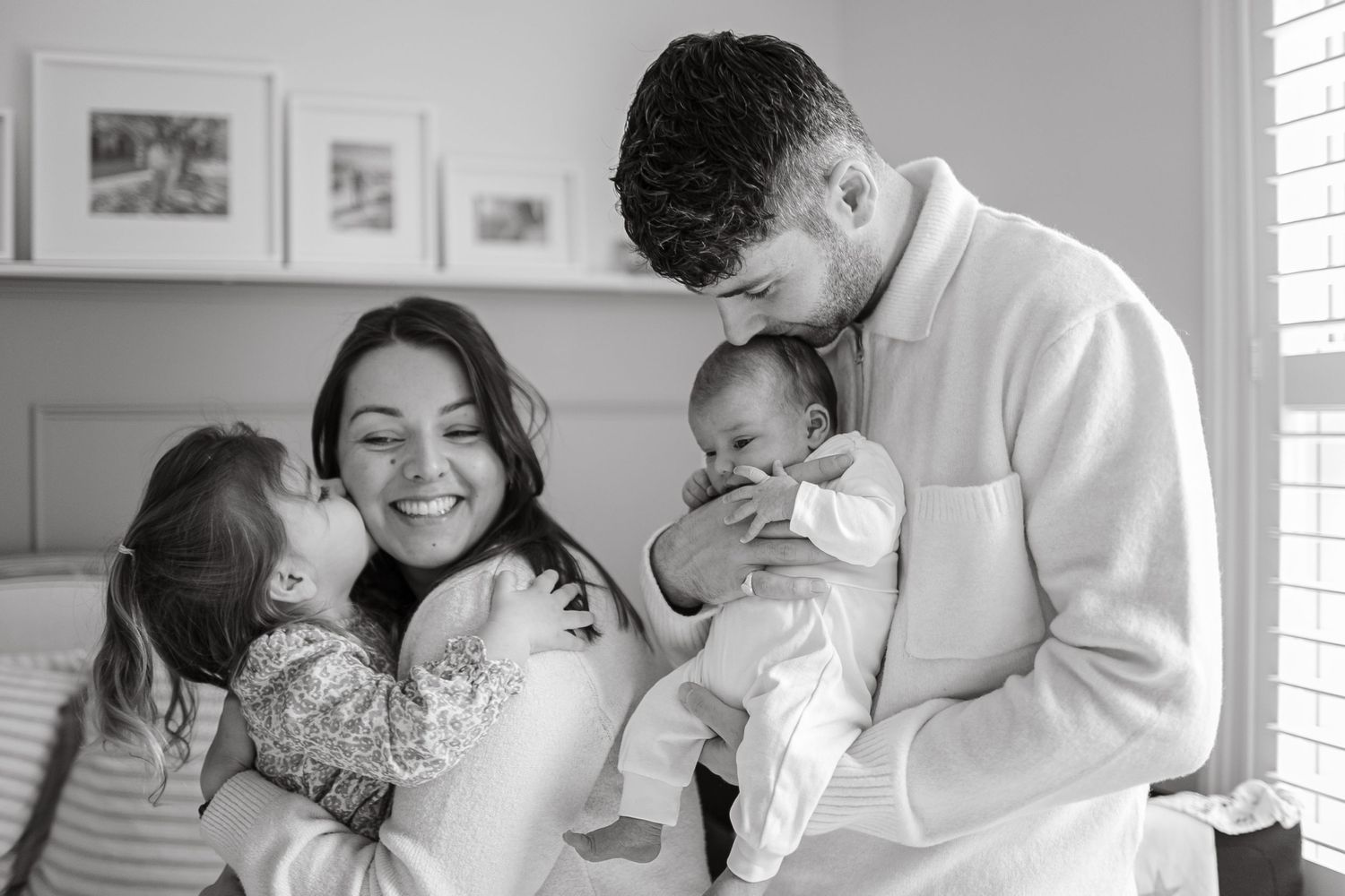 A family sharing joyful moments together in a bedroom with wall art.