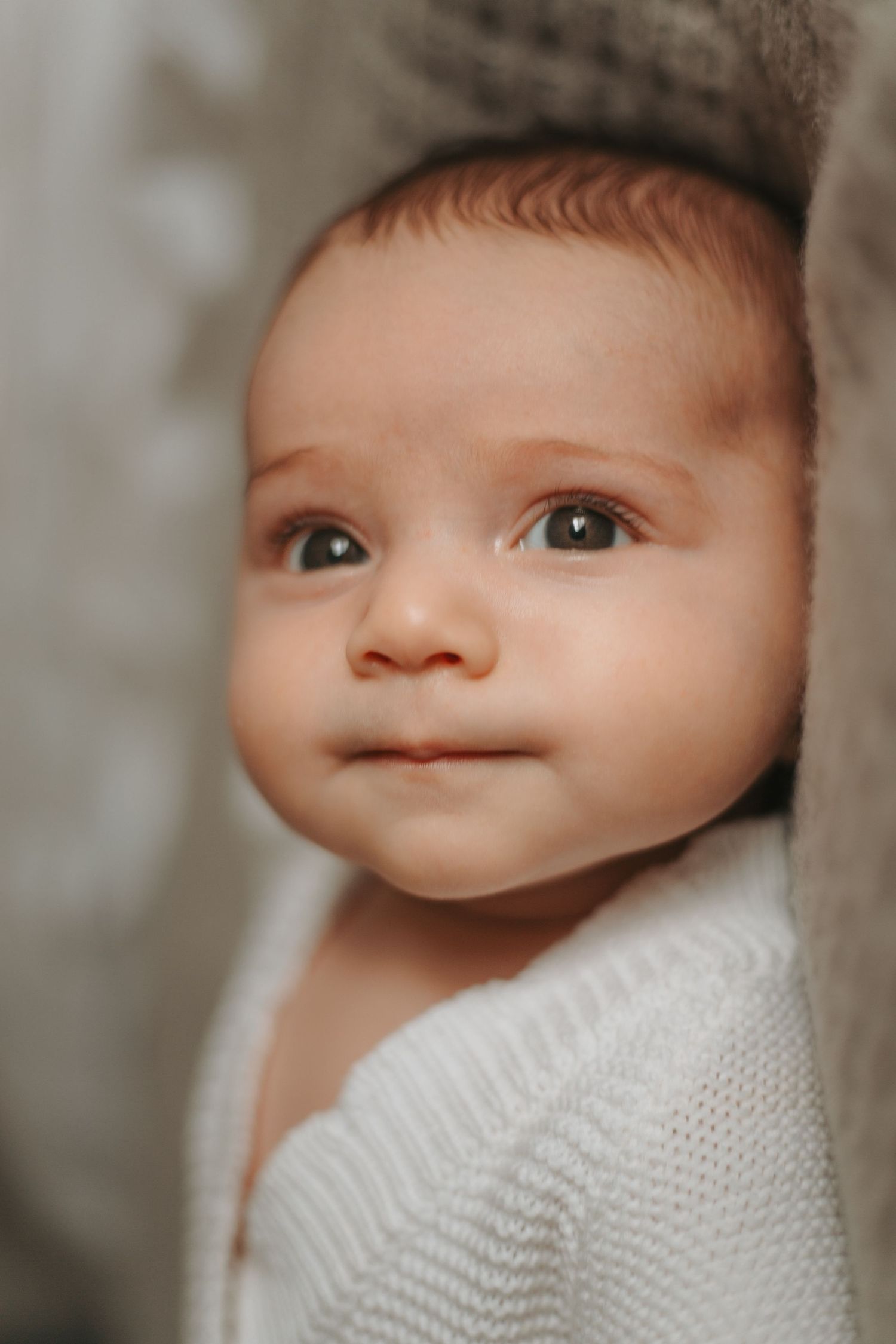 Artistic close-up portrait showing newborn baby's eyes and features in soft lighting.