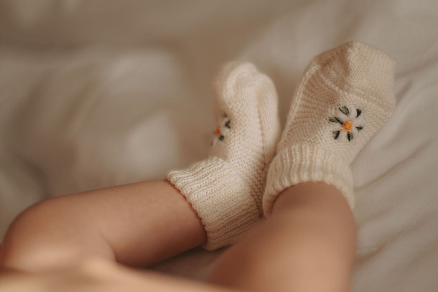 Soft focus detail shot of baby wearing cream knit clothing during photo session.